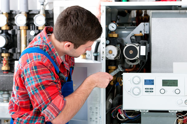 HVAC technician inspecting and repairing boiler controls in Boulder